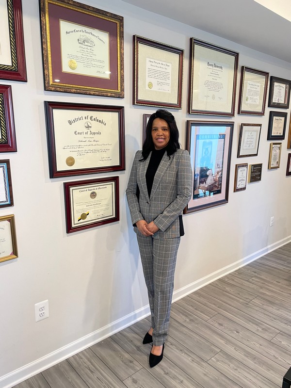 Debora A Borges standing by her achievement wall